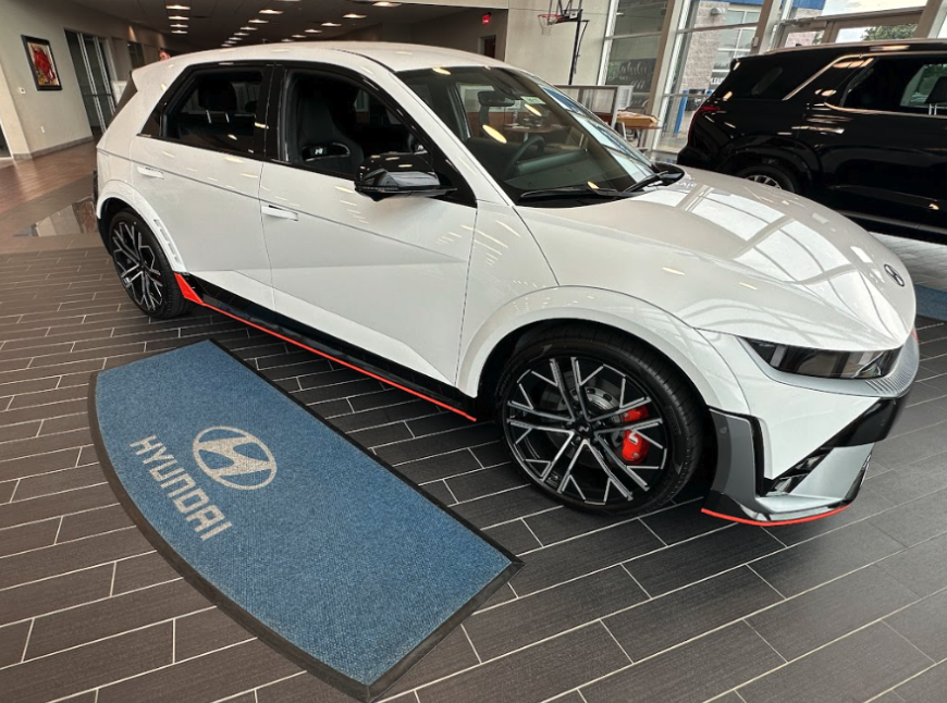 White Hyundai Ioniq 5 N on display in a showroom at Crain Hyundai of Fayetteville, highlighting sleek design and red performance accents.